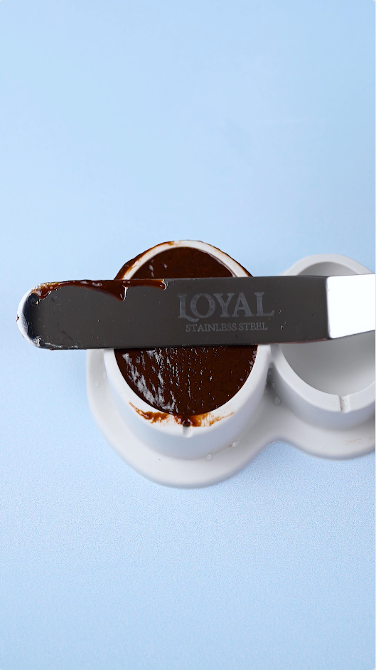 Smoothing out chocolate truffle mixture with a LOYAL Bakeware angled spatula to create half a chocolate truffle egg.