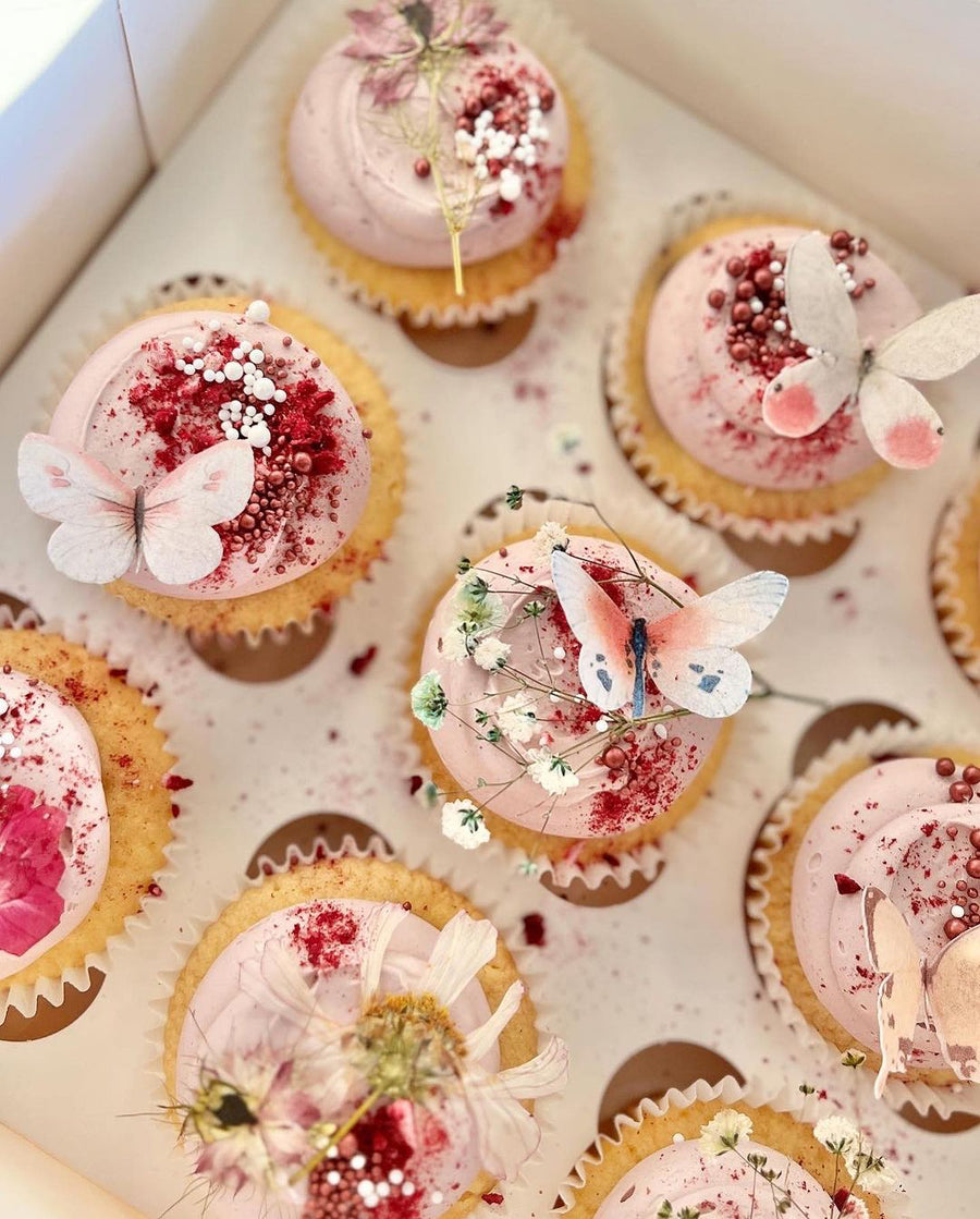 Cupcakes decorated with butterflies, flowers and sprinkles using Colour Mill Mauve Oil Blend